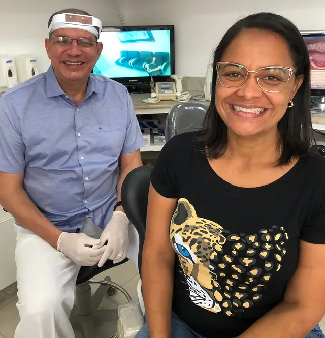 Dr. Douglas César no consultório com paciente sorrindo após o tratamento ortodôntico
